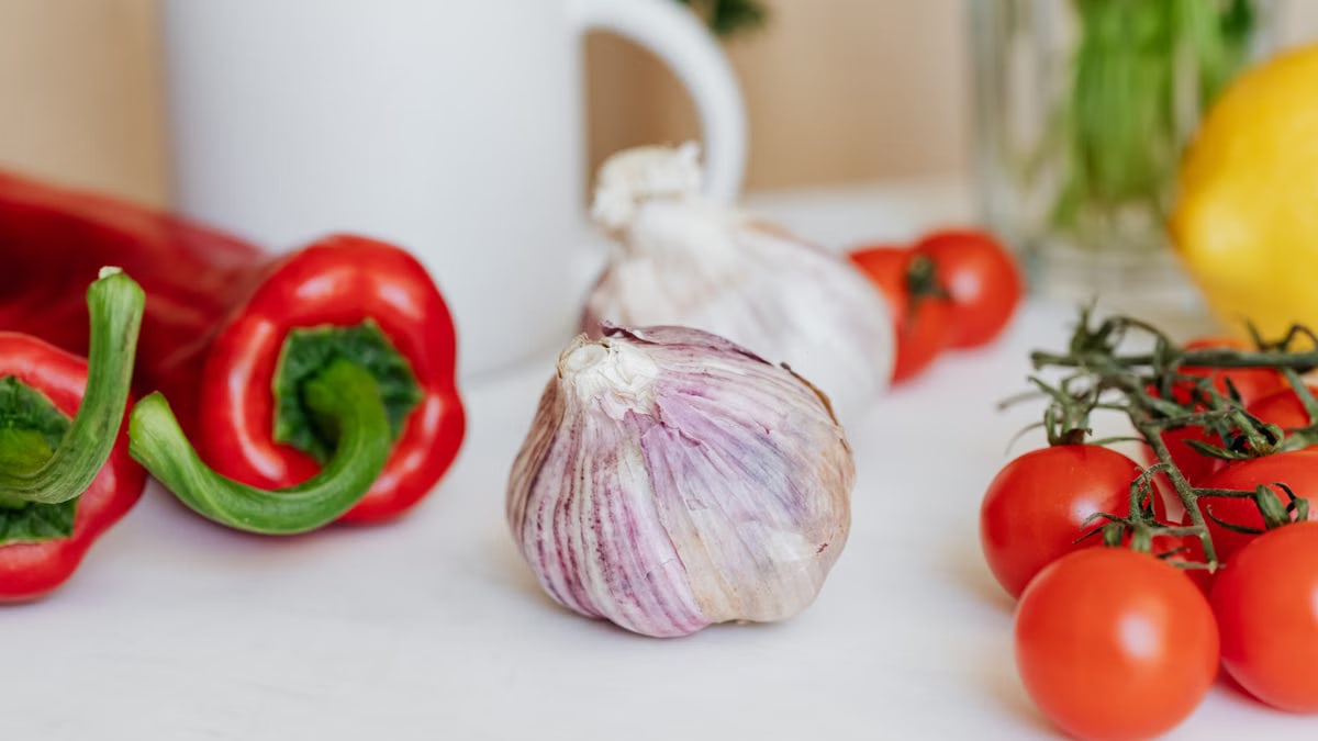 Close-up of fresh tomatoes, garlic, and red peppers on a white table, ideal for culinary projects.